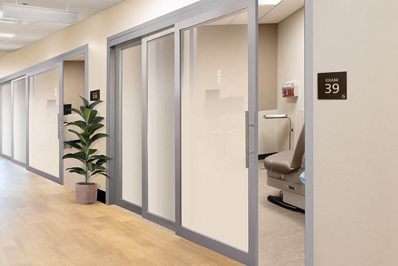 Corridor in health care center featuring telescopic sliding doors for each room.