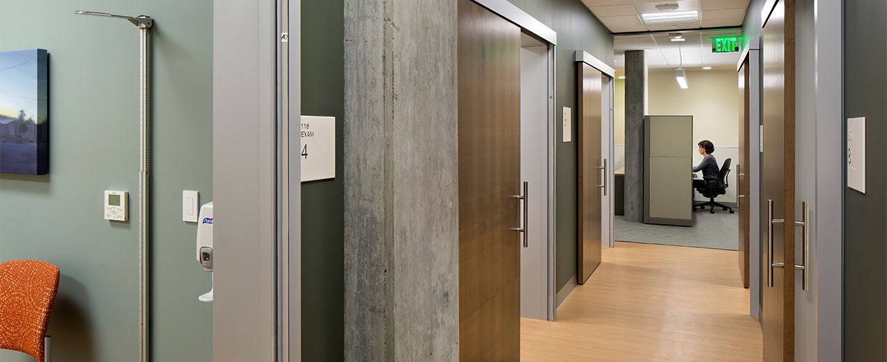 Close up image of sliding exam room doors lining the hallway in a healthcare facility.