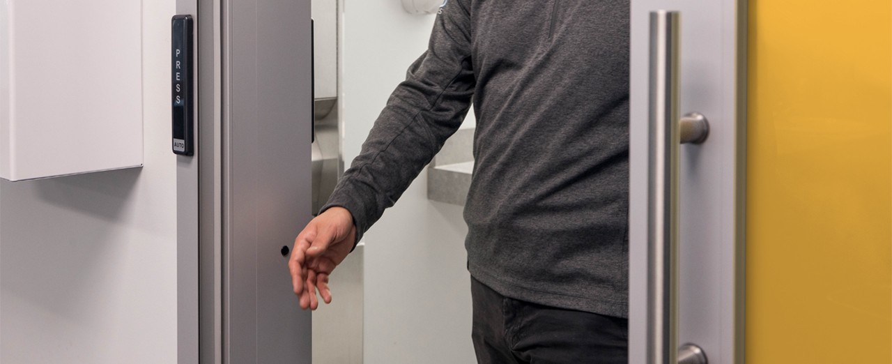 Patient using a yellow automatic sliding door to exit a room.