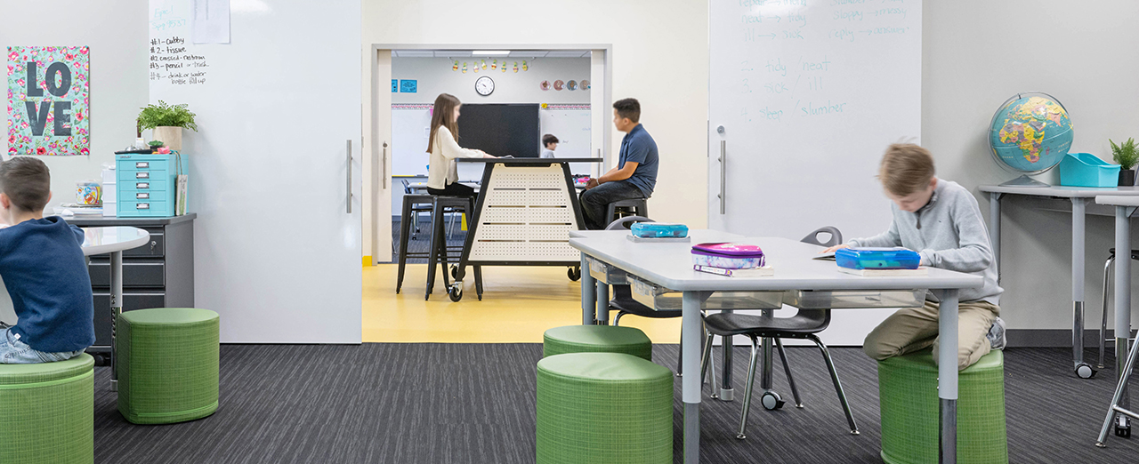 Whiteboard sliding doors used to split a classroom into multiple spaces with children working in different parts of the classroom.