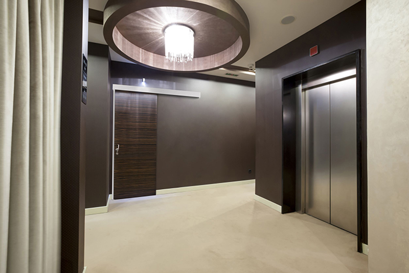 Elegant hotel lobby with contemporary decor, featuring a large wooden sliding door and a sleek elevator, enhancing the luxury hospitality experience.