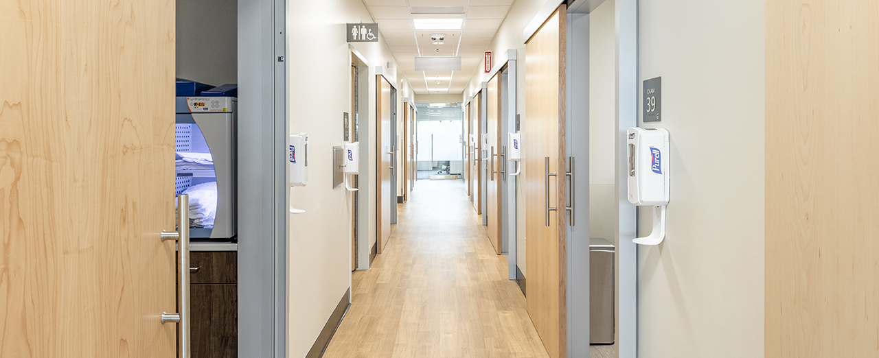 Hallway in a healthcare facility featuring modern patient room sliding doors.