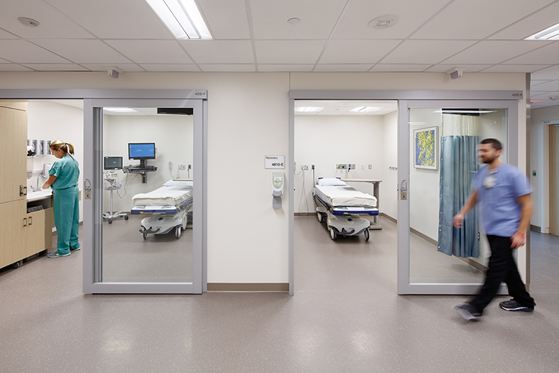 Modern health care facility with sliding glass doors showing two recovery rooms.